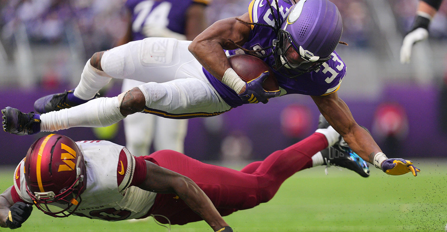Dec 7, 2025; Minneapolis, Minnesota, USA; Minnesota Vikings running back Aaron Jones (33) rushes the ball against Washington Commanders safety Tyler Owens (18) during the second half at U.S. Bank Stadium. Mandatory Credit: Brad Rempel-Imagn Images